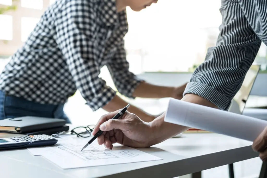 Zwei Personen arbeiten gemeinsam an Plänen und Unterlagen – Symbol für strukturierte und verlässliche Hausverwaltung